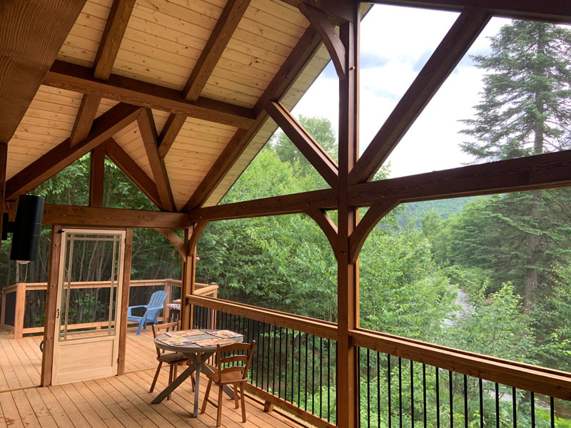 Vue de la terrasse immense comprenant un espace détente au Chalet de la Rivière, hébergement situé aux abords de la rivière et profitant d'une vue magnifique sur les montagnes et la nature environnante de la Vallée.