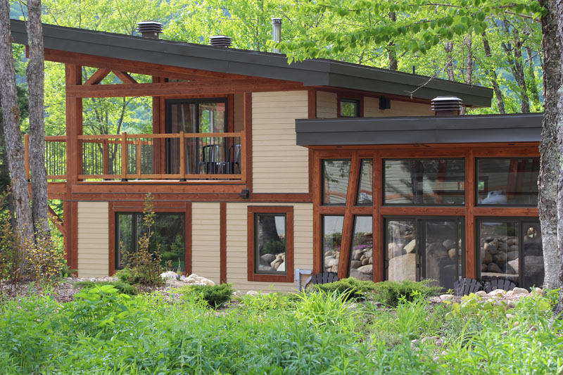 Façade faite de bois massif de l'un des chalets disponibles pour la location à la Vallée, le chalet Kame, l'un des types d'hébergements offerts pour vos séjours de plein air entourés par la nature et les montagnes magnifiques.